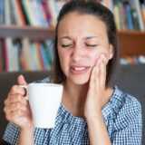 Person holding cup feeling tooth pain
