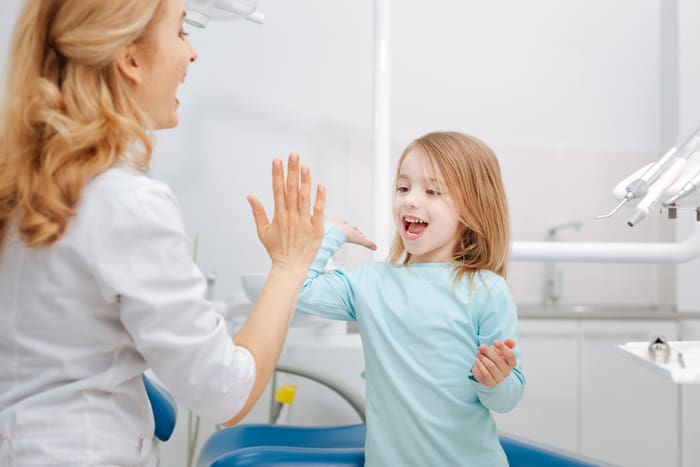smiling girl with female pediatric endodontist after some dental procedures
